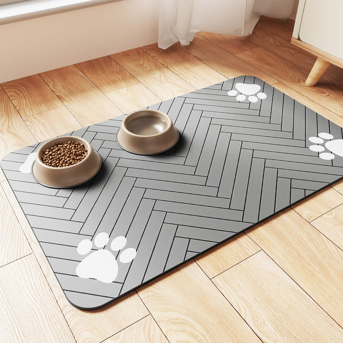 Angled view of the grey herringbone pet feeding mat with two round bowls on a wood floor