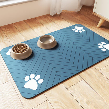 Blue herringbone pet feeding mat with paw-print corners holding a food bowl and water bowl